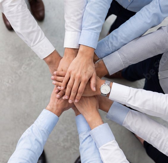 Hände eines Teams übereinander als Zeichen des Zusammenhalts